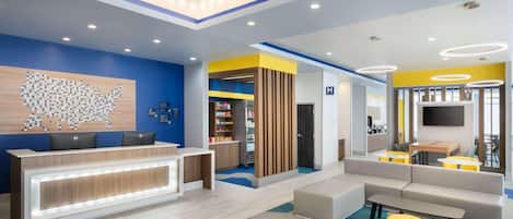 A modern reception area with a desk, seating, and a large wall art piece.