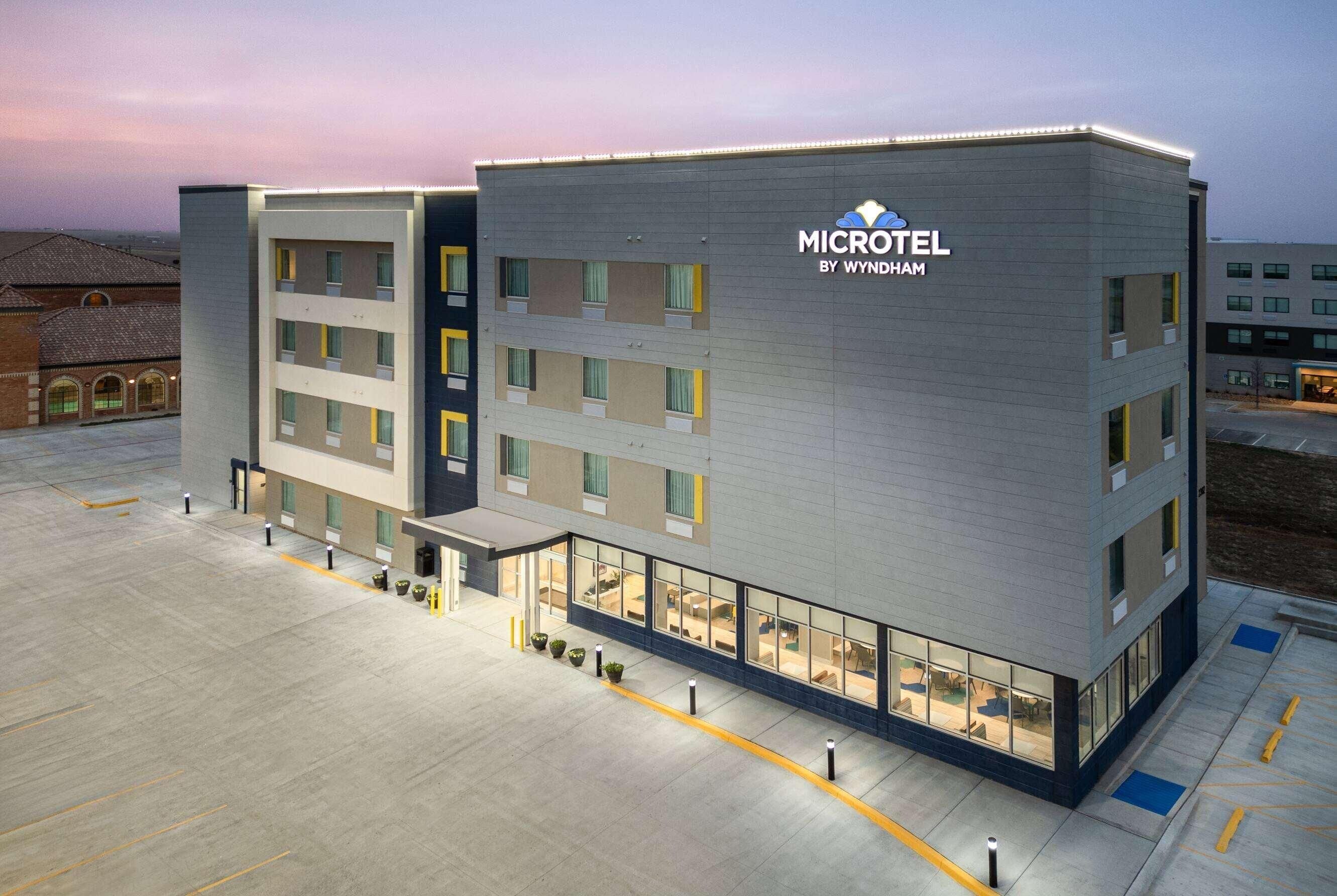 Un microhotel moderno con fachada plana, varios balcones y una entrada bien iluminada.