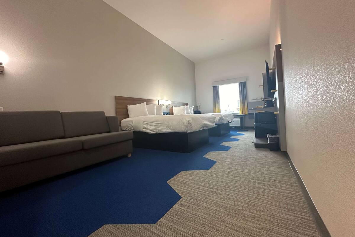 A hotel room with a bed, a sofa, a TV, and a desk.