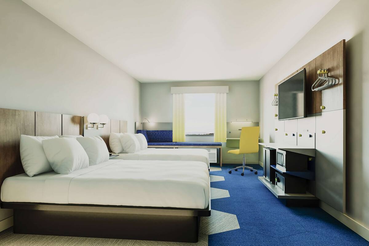 A hotel room with a bed, a desk, a chair, a TV, and a window with curtains.