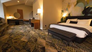 Habitación de hotel con una cama grande, un escritorio y una zona de estar.