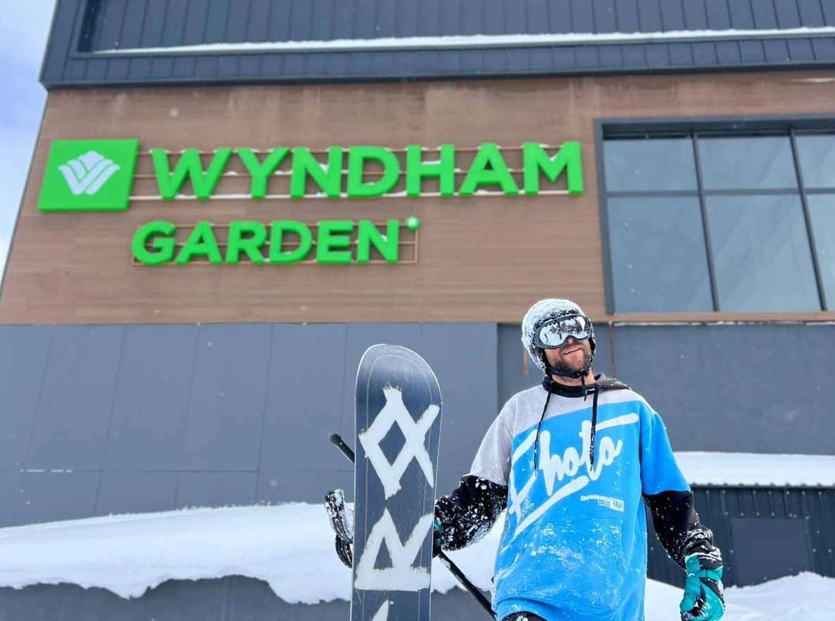 A person standing in front of a building with a sign that reads 'WYNDHAM GARDEN'.