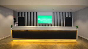 Una recepción con una pantalla digital que muestra "WYNDHAM GARDEN Cambai".