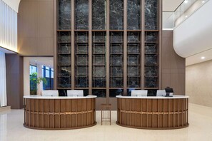 A reception area with two wooden reception desks, a marble wall, and a glass railing. - Days Inn By Wyndham Linyi Yihe New Area (Linyi)