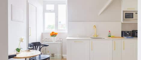 A modern kitchen with white cabinetry, a stainless steel sink, and a Bosch microwave.