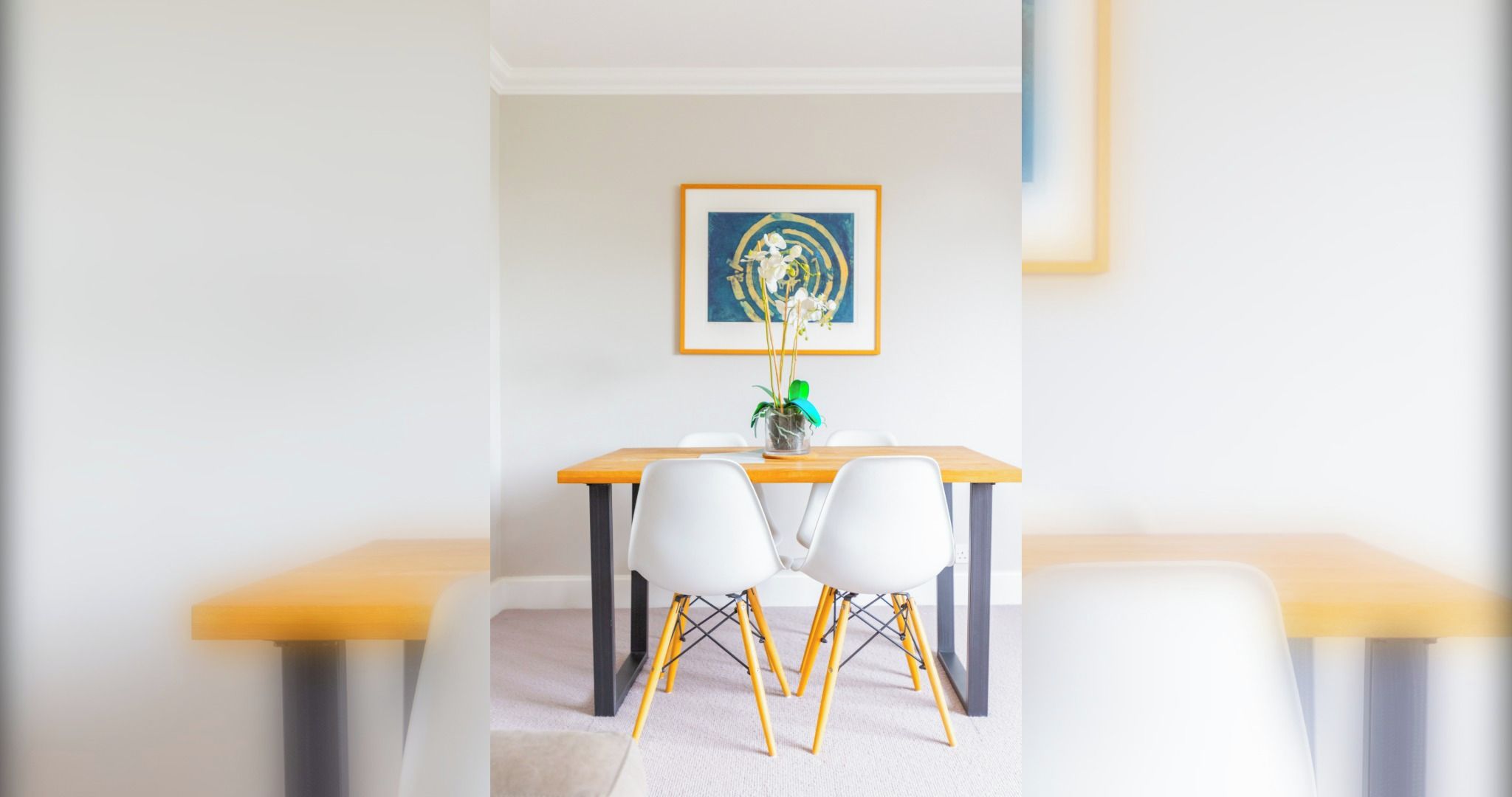 Un coin repas avec une table en bois, des chaises blanches et une plante en pot.