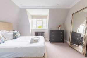 A bedroom with a bed, a dresser, a mirror, a radiator, and a window.