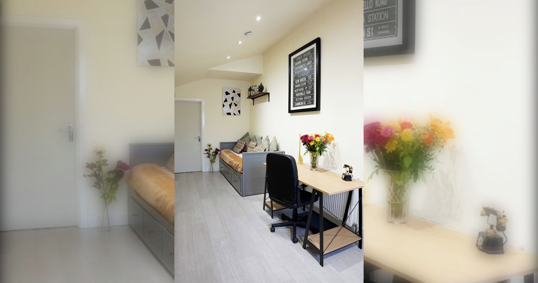 A modern bedroom with a bed, a desk, and a chair. There is a vase with flowers on the desk.