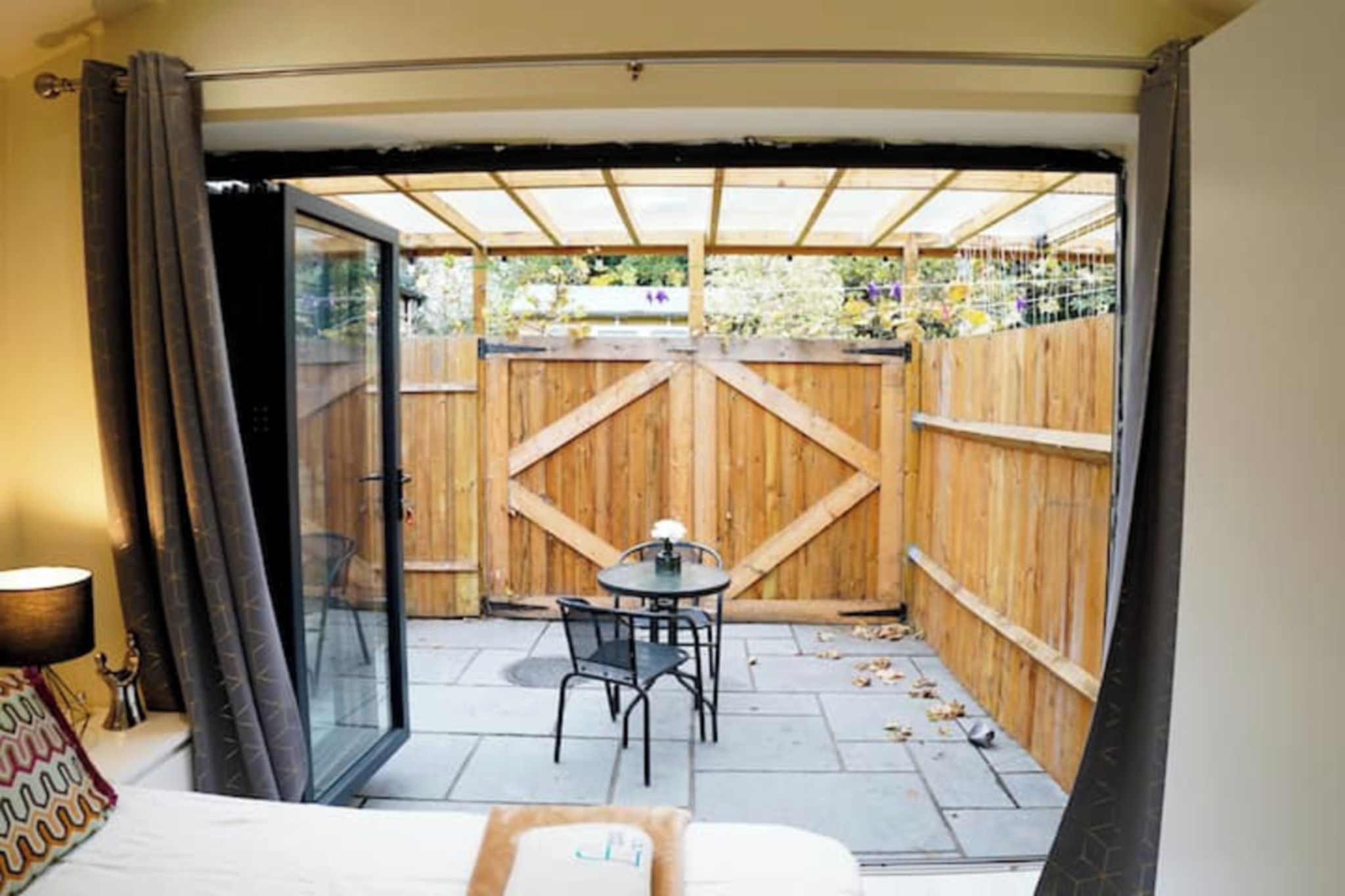 Une pièce dotée d’une porte vitrée donnant sur un patio extérieur, agrémenté d’une clôture en bois, d’une table et de chaises.