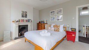 A bedroom with a large bed, a fireplace, a red nightstand, and a bookshelf. - Delightful 3BD Home with Garden in North London (London)