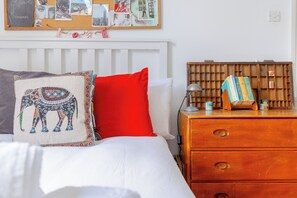 A neatly made bed with a patterned pillow, a red pillow, and a white comforter. - Delightful 3BD Home with Garden in North London (London)