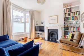 A living room with a sofa, a fireplace, a bookshelf, and a television.