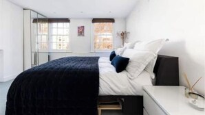 Une chambre à coucher avec un lit, une table de chevet et une fenêtre.