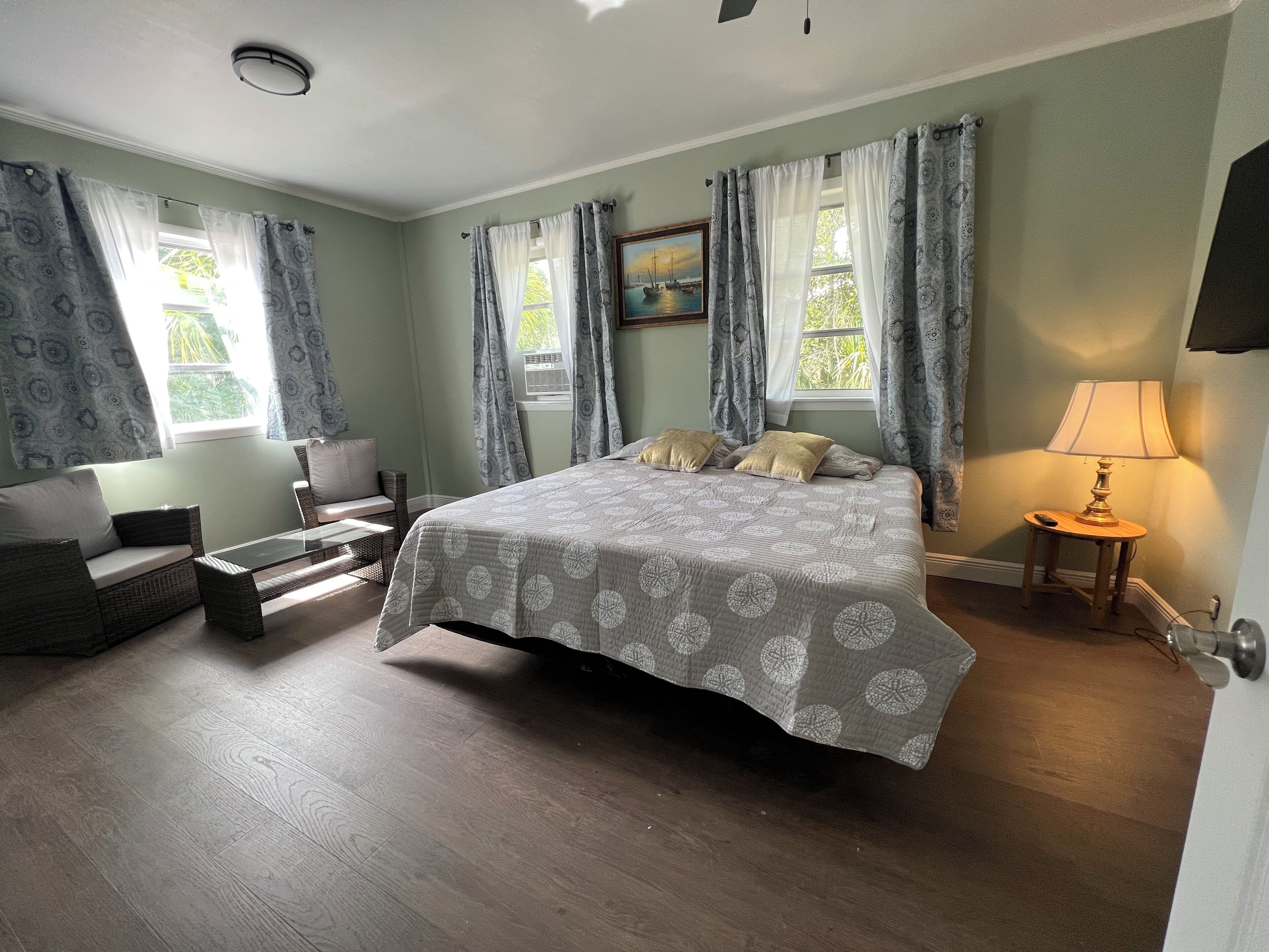 A bedroom with a bed, a sofa, a small table, and a lamp.