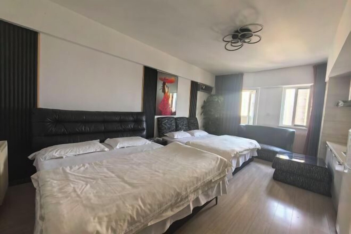 Habitación de hotel con dos camas, un ventanal grande y un ventilador de techo.