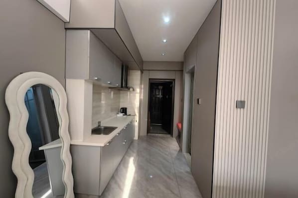 Una cocina moderna con encimera blanca, horno integrado y pileta de acero inoxidable.