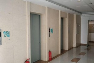 A hallway with doors, a fire extinguisher, and a sign on the wall.