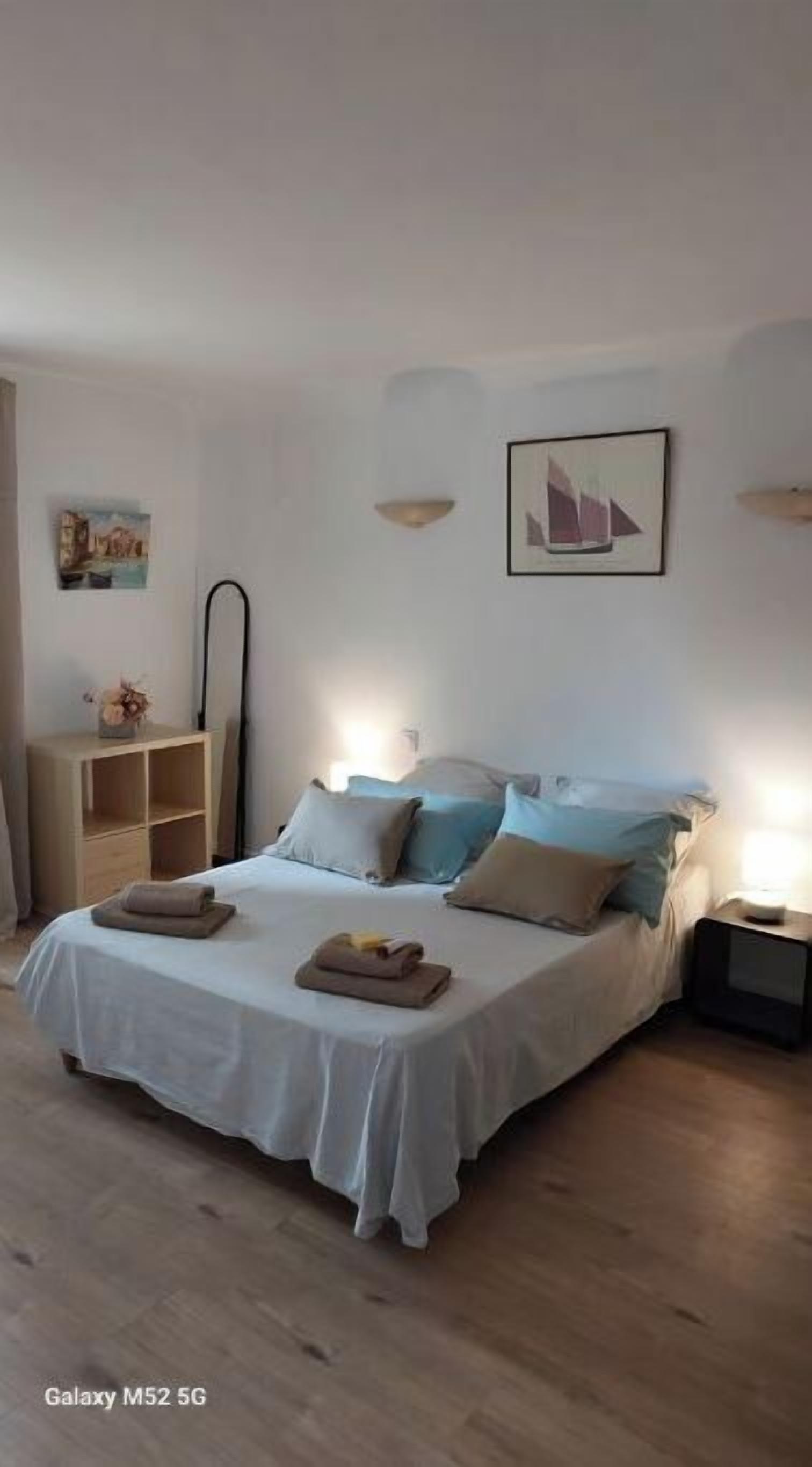 Una camera da letto con un letto, comodini, uno specchio e opere d'arte alle pareti.