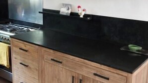 A kitchen with wooden cabinets, a black countertop, and a stainless steel range hood. - Bright, quiet apartment with private pool (Vaison-la-Romaine)