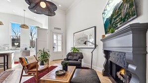 Una sala de estar moderna con chimenea, muebles de cuero y un amplio ventanal.