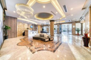 Un vestíbulo amplio con mostrador de recepción, zona de estar y ventanas grandes.