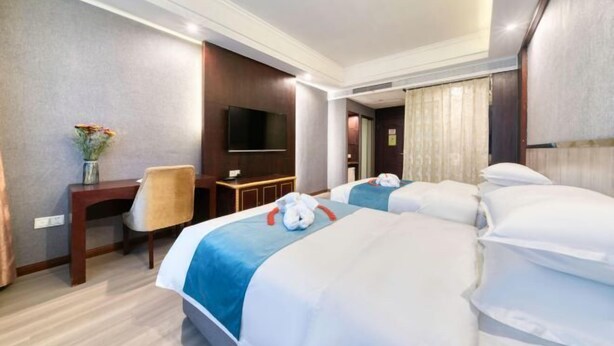 A hotel room with two beds, a desk, a chair, a TV, and a window with curtains. - Chuangejia Golden Lotus Hotel (Yongkang Stadium Chengnan Road Store) (Yongkang)