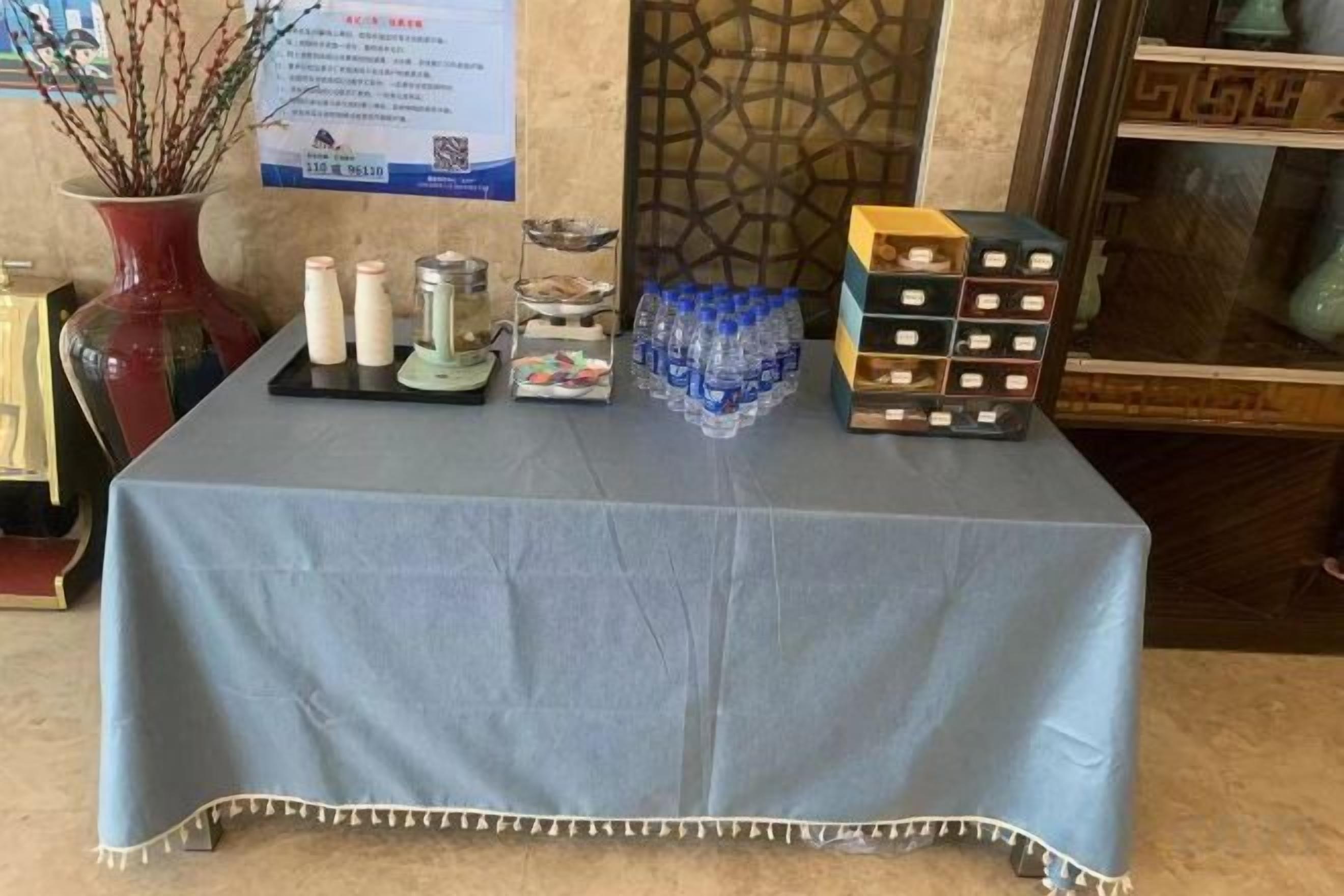 A table with a blue tablecloth, containing various items including bottles, a tray, and a box of tissues.