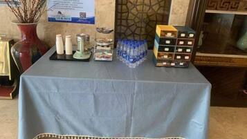 A table with a blue tablecloth, containing various items including bottles, a tray, and a box of tissues.