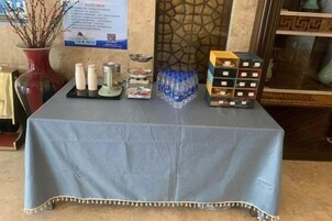 Una mesa con mantel azul, que contiene varios objetos, incluyendo botellas, una bandeja y una caja de pañuelos.