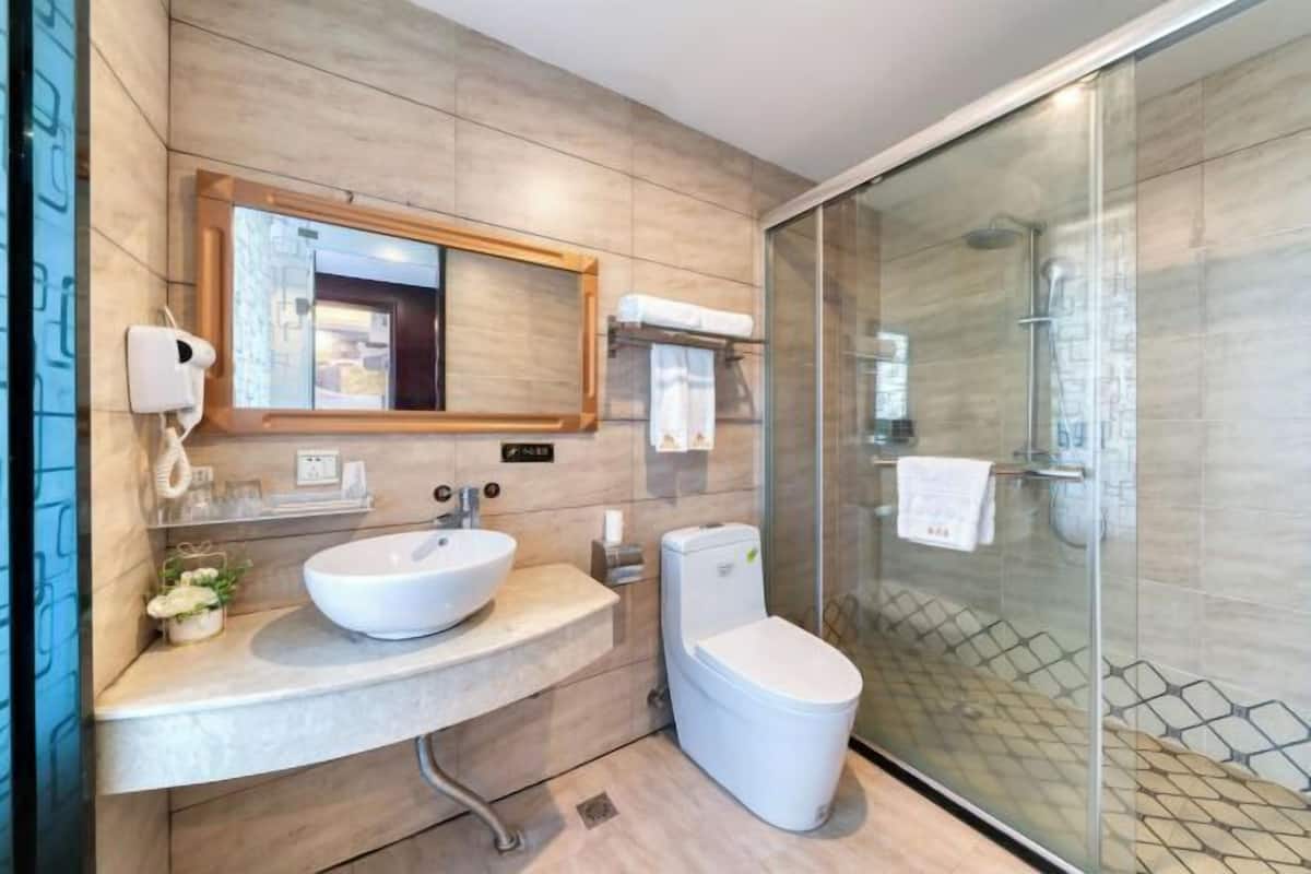 A modern bathroom with a large sink, toilet, and glass shower enclosure.