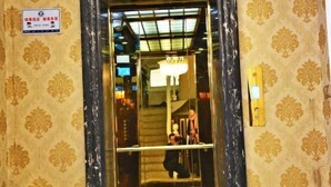 A hotel entrance with a marble frame, a sign with Chinese characters, and a staircase leading inside. - Xindu Hotel (Wenzhou)