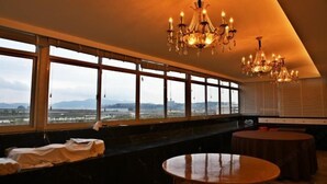 A hotel room with large windows, a chandelier, a round table, and a bench. - Xindu Hotel (Wenzhou)