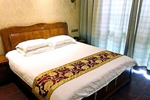 A neatly made bed with a white duvet and a decorative red and gold bedspread. - Xindu Hotel (Wenzhou)