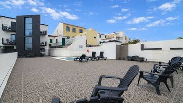A rooftop terrace with a pool, lounge chairs, and a view of buildings.