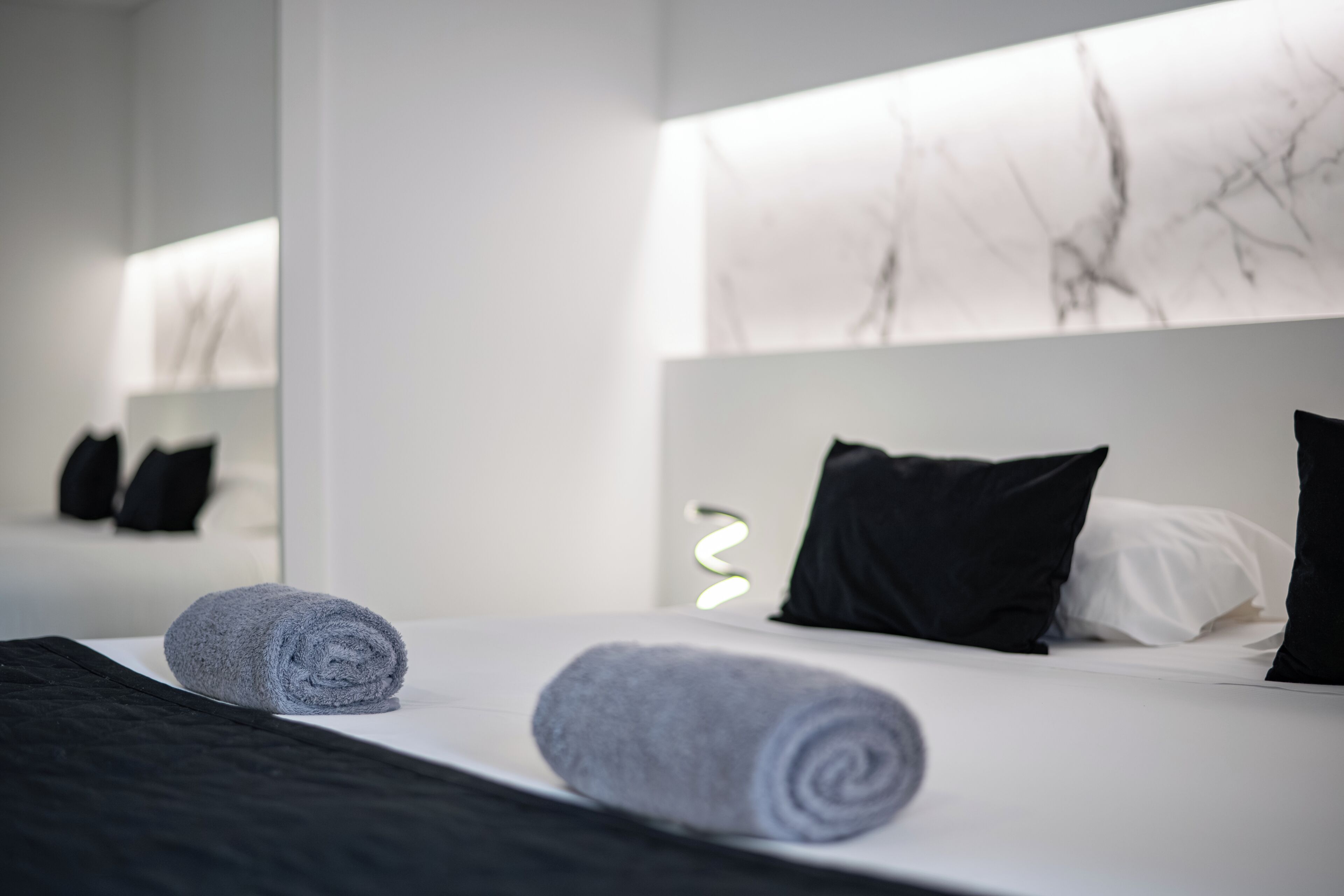 Quarto de hotel com cama bem arrumada, um espelho grande e um design moderno na parede.