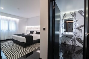 A modern hotel room with a large bed, a marble bathroom, and a geometric patterned rug. - The Rock Hostel (Ponta Delgada)