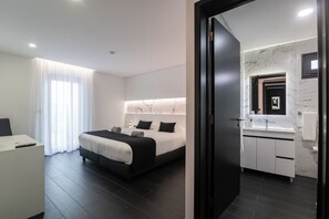 A modern hotel room with a bed, bedside table, and a bathroom with a marble sink. - The Rock Hostel (Ponta Delgada)