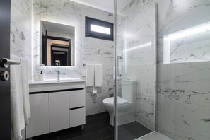 A modern bathroom with a glass shower enclosure, a white toilet, and a marble backsplash. - The Rock Hostel (Ponta Delgada)