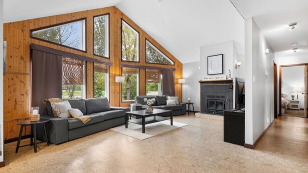 Un salon spacieux doté d’une grande fenêtre, d’une cheminée et d’un canapé moderne.