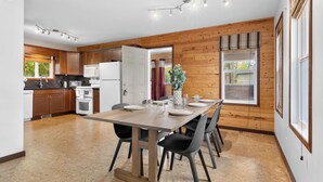 Une cuisine moderne avec des meubles en bois, une table à manger avec des chaises et une grande fenêtre avec des rideaux.