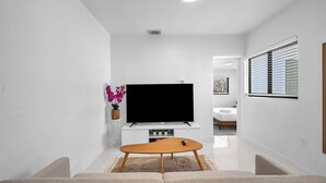 A modern living room with a flat-screen TV, a wooden coffee table, and a beige sofa. - Villa Roads 2/2 King Bed, Laundry Coral Gables, Brickell, Little Havana, Airport (Miami)
