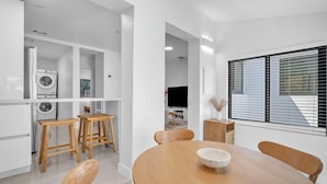 Una cocina moderna con electrodomésticos integrados, taburetes de madera y una mesa de comedor con sillas.