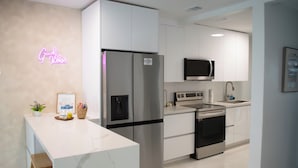 Una cocina moderna con armarios blancos, electrodomésticos de acero inoxidable y encimera de mármol.
