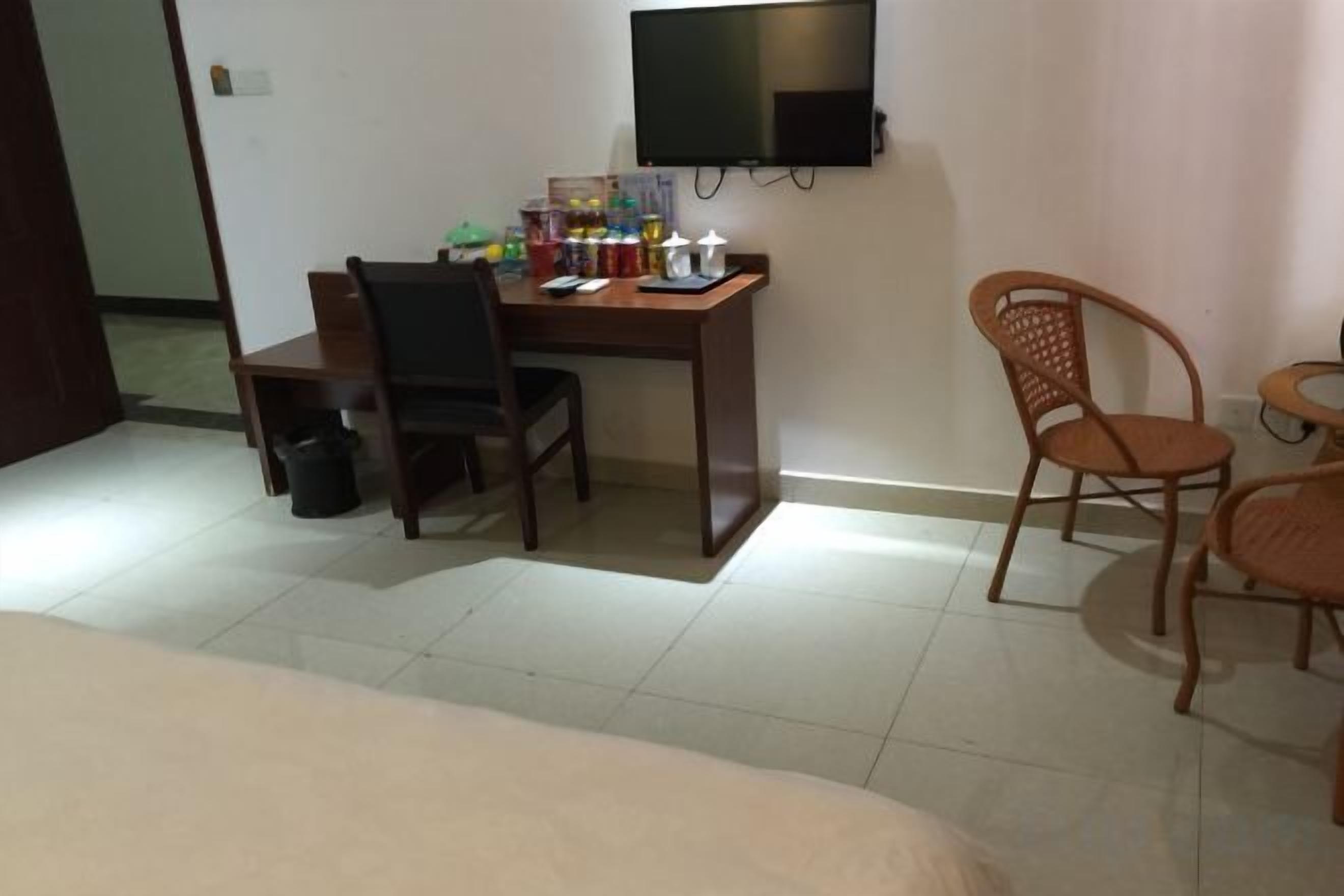 A hotel room with a bed, a desk, a chair, a television, and a small table.