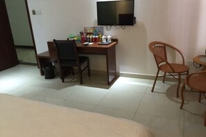 Une chambre d’hôtel comprenant un lit, un bureau, une chaise, un téléviseur et une petite table.