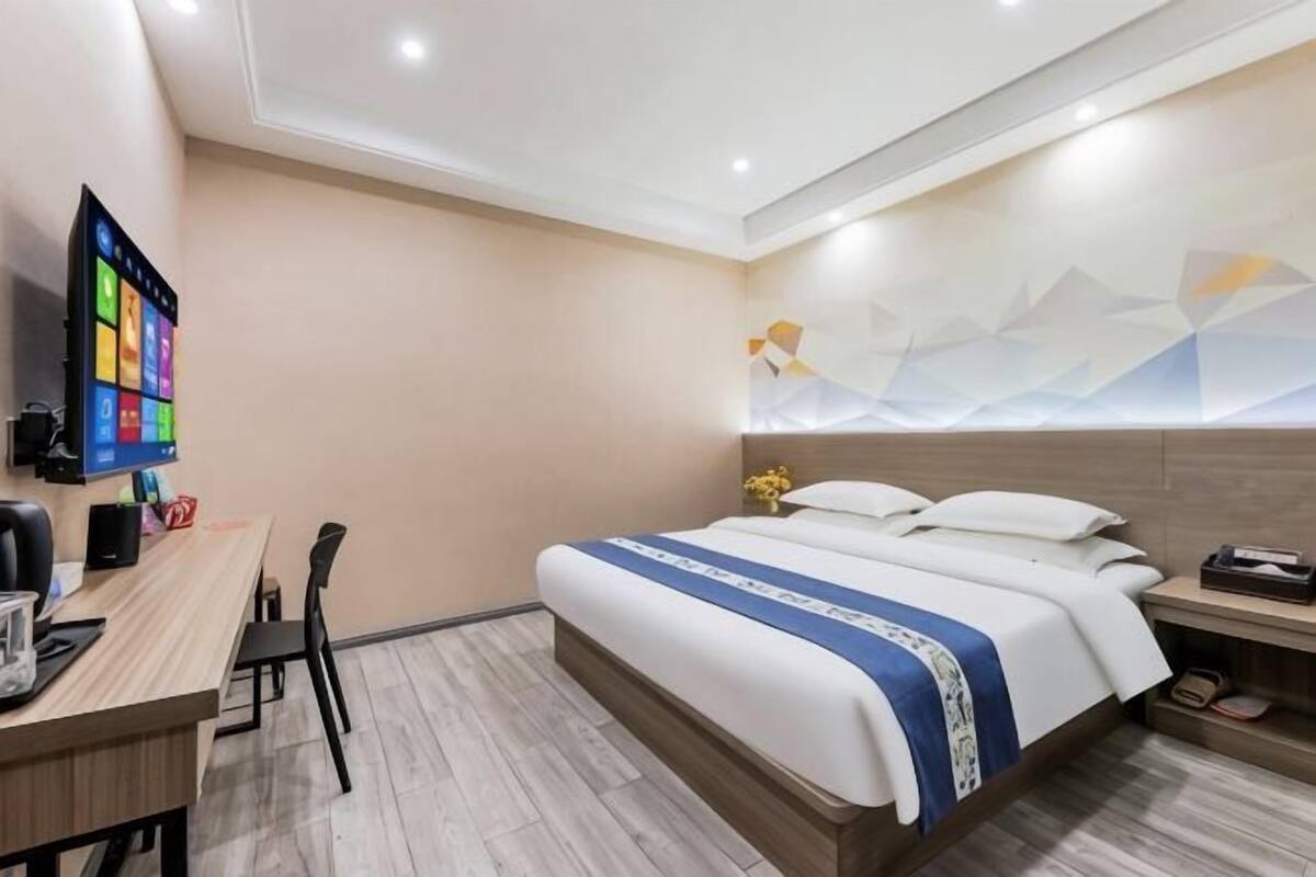 Una habitación de hotel con cama, escritorio, silla y televisor.