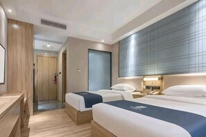 Ett hotellrum med två sängar, ett skrivbord och ett stort fönster med persienner.