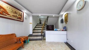 Un espace d’accueil comprenant un comptoir de réception, un escalier, un canapé et une horloge murale.