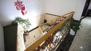 Un escalier doté d’une rampe en bois et de balustrades en métal, agrémenté de fleurs rouges et de verdure.