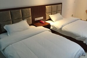 Habitación de hotel con dos camas, una mesita de noche con teléfono y un interruptor de luz en la pared.